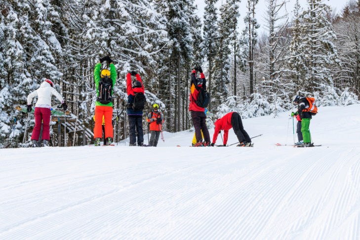 Aufwärmübungen zum Start eines Skitages helfen dabei, Verletzungen zu vermeiden.